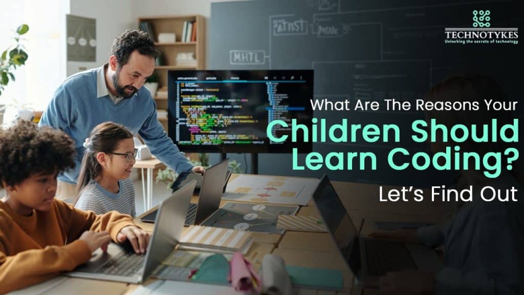 Young children learning coding with a teacher in a classroom setting, using laptops and a large scre.