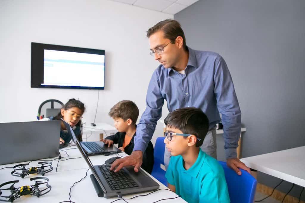Teacher guiding children in a computer coding class at Techno Tykes.