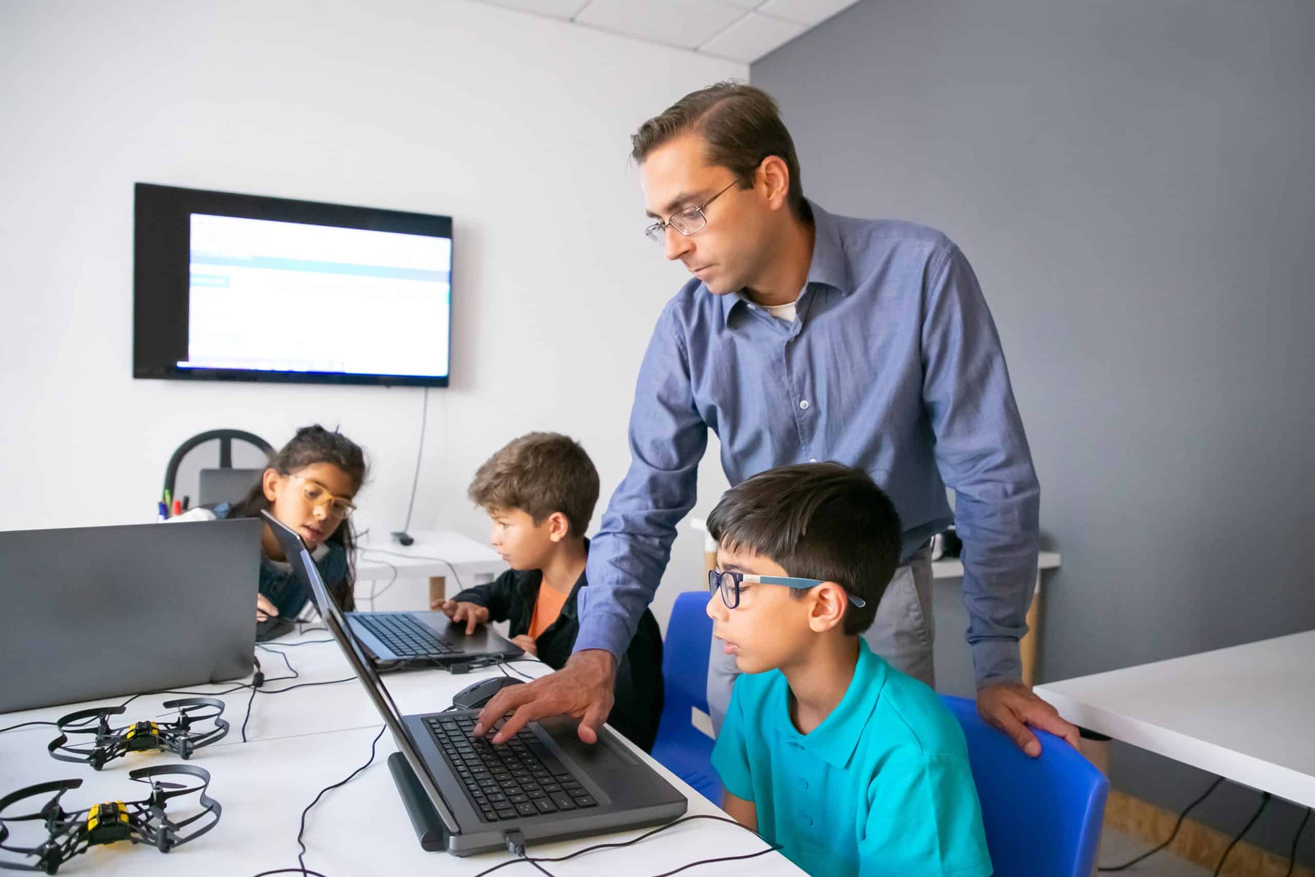 Teacher guiding children in a computer coding class at Techno Tykes.